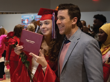 girl holding diploma with dad